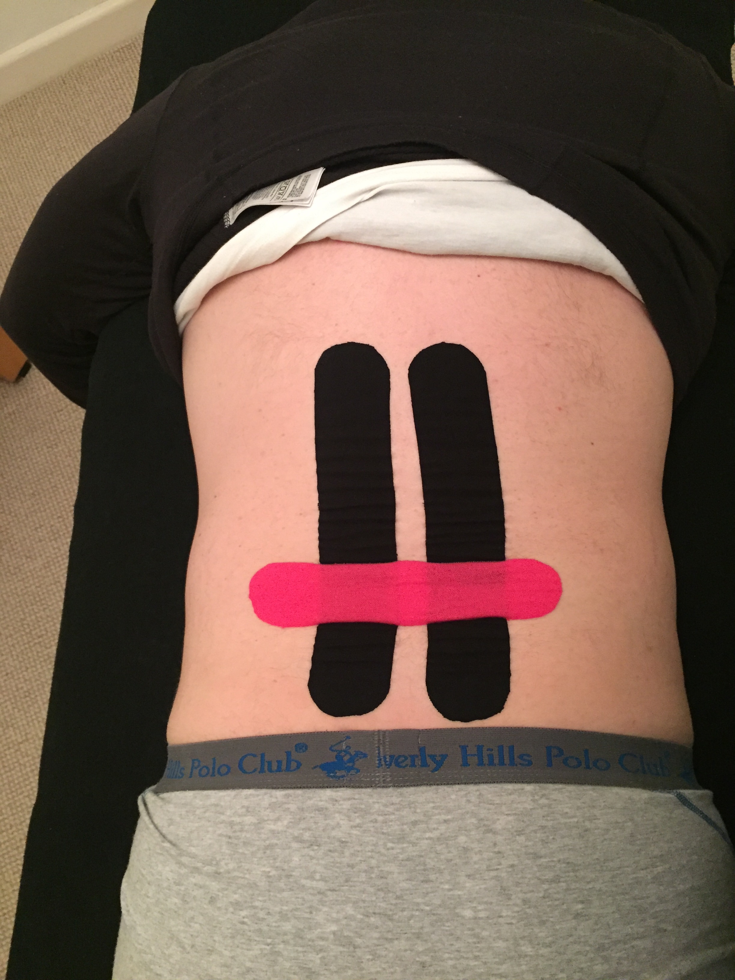 Two vertical black tape strips either side of the lower spine with one horizontal pink strip across them